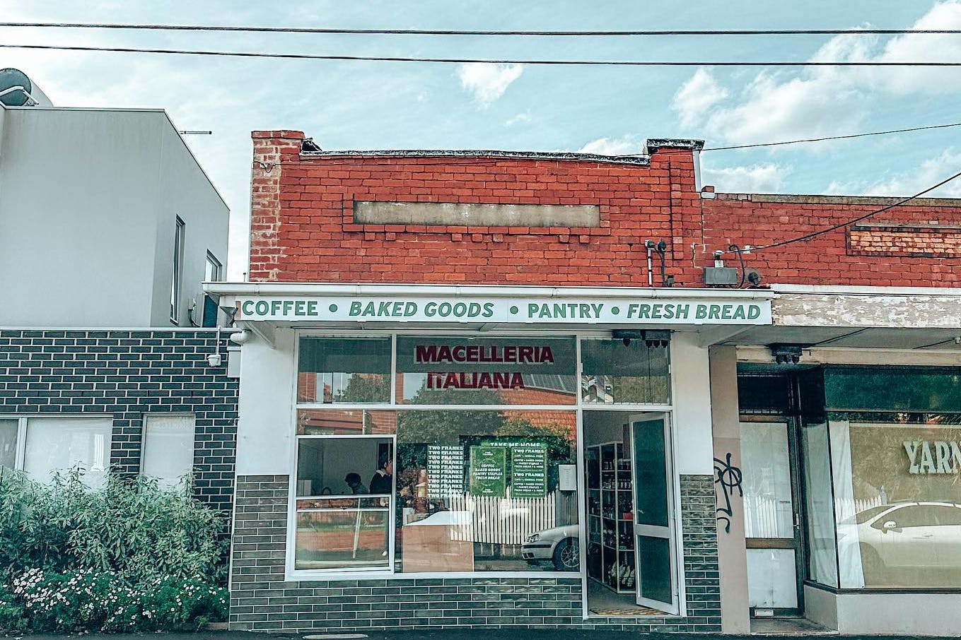 A shopfront of a milk bar in a quiet street.